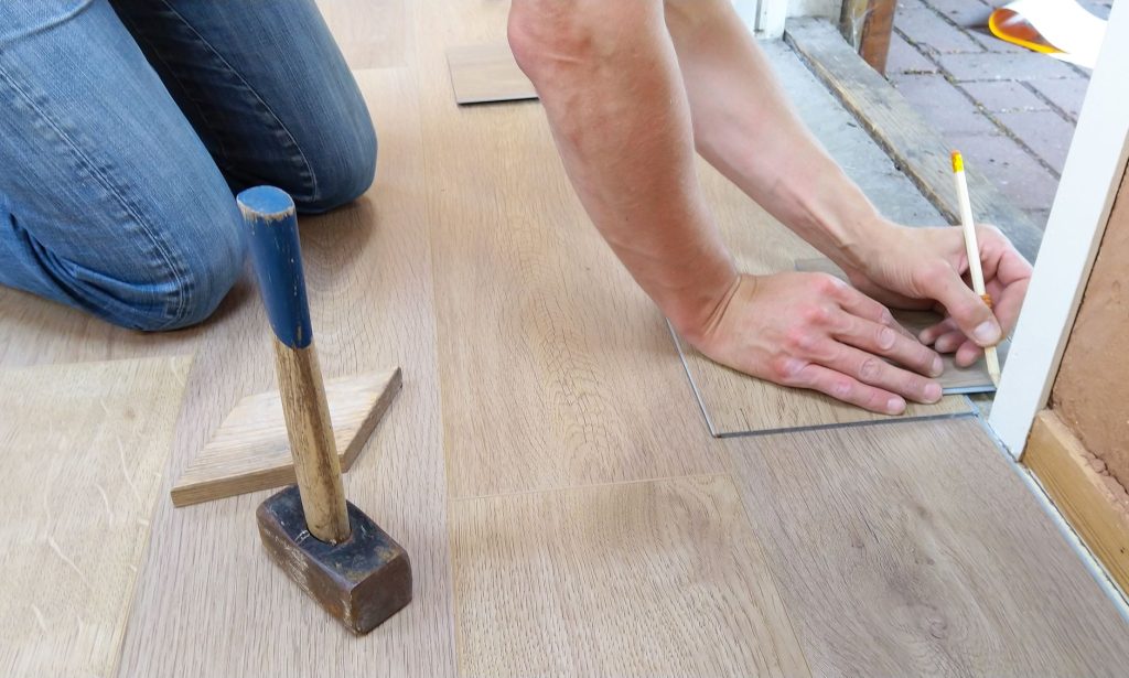 Fußbodenverlegung – Bodenleger misst und markiert Dielen beim Verlegen