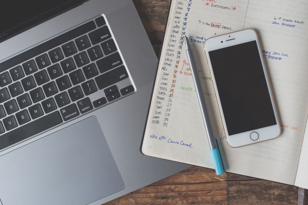Virtuelle Assistenz organisiert – Laptop, Smartphone und Planer auf dem Schreibtisch