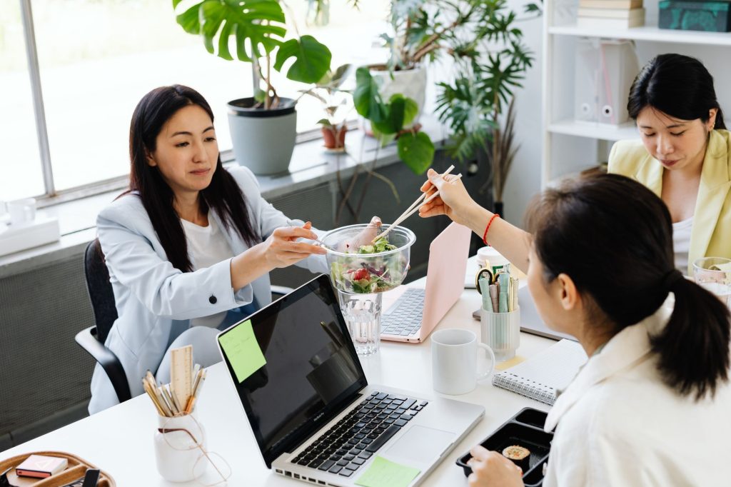 Gesunde Ernährung im Startup – Kolleginnen teilen einen Salat in der Mittagspause
