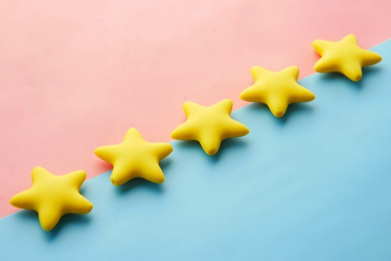 Warum Start-ups von Tag eins an Feedback sammeln sollten a row of yellow stars sitting on top of a blue and pink surface