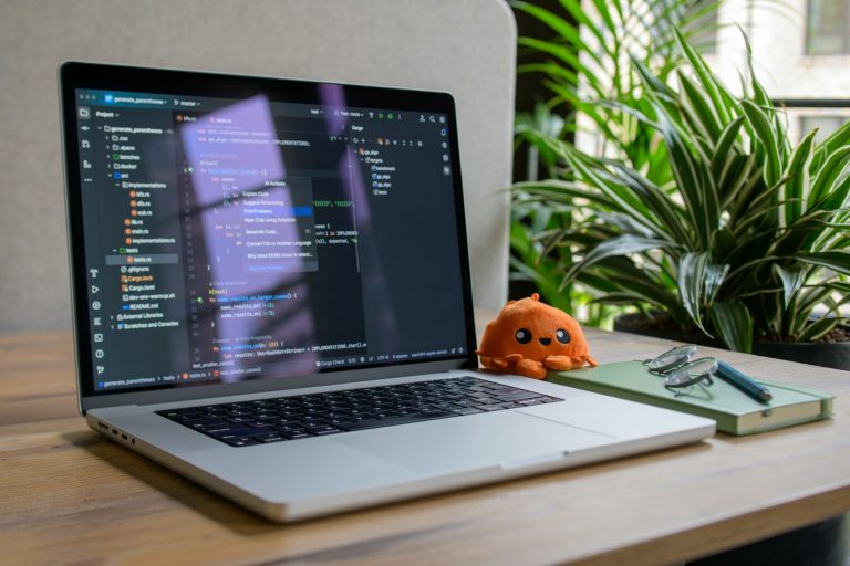 Wie Automatisierung das Einziehen von Zahlungen deutlich vereinfacht Laptop displaying code with small stuffed toy nearby