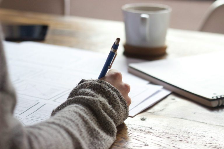 Der unsichtbare Erfolgsfaktor: Wie professionelle Textüberarbeitung Manuskripte in Bestseller verwandelt person writing on brown wooden table near white ceramic mug
